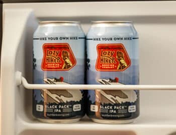 Two cans of Lazy Hiker Brewing Company's Slack Pack IPA sit on a refrigerator shelf.